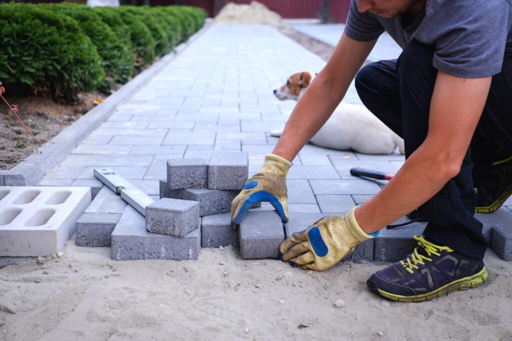 The master in yellow gloves lays paving stones